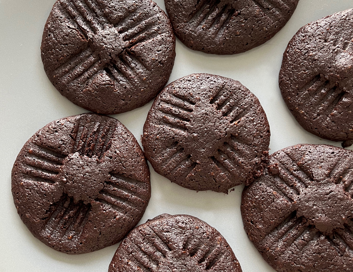soft dark brown hazelnut cacao cookies with four fork indents around each cookie